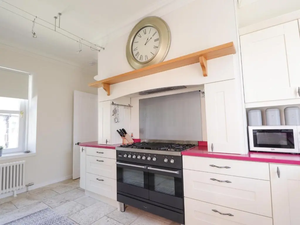 a kitchen with a stove and a clock on the wall at Mary Ann Villa in Inverness