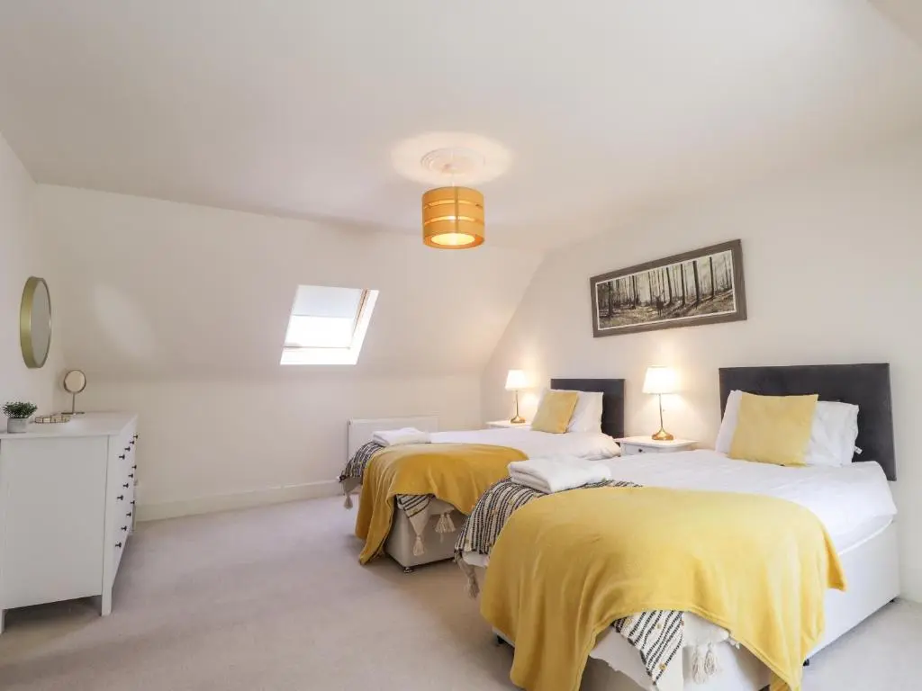 two beds in a white room with yellow blankets at Mary Ann Villa in Inverness