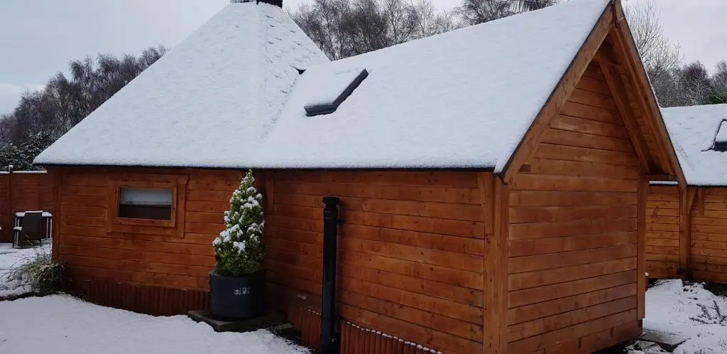 a wooden cabin with a snow covered roof at Unique luxury cabin 2 in Inverness