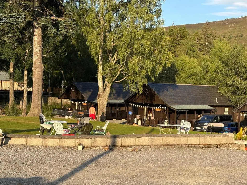 a house with chairs and tables in front of it at Braemar Lodge Cabins Not for profit in Braemar