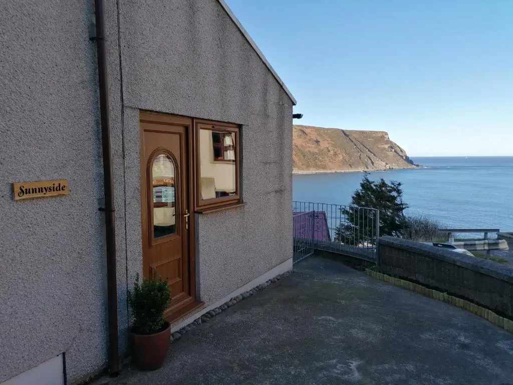 a door to a building with a view of the ocean at Sunnyside House in Gardenstown