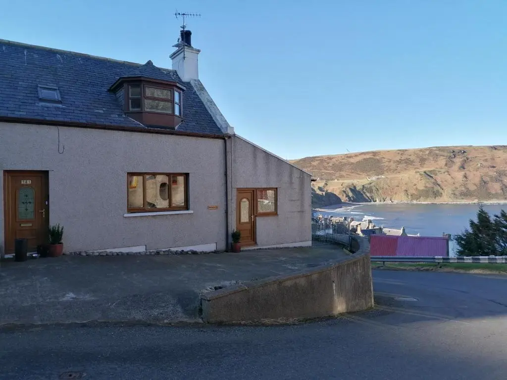 a house on the side of a road with a beach at Sunnyside House in Gardenstown