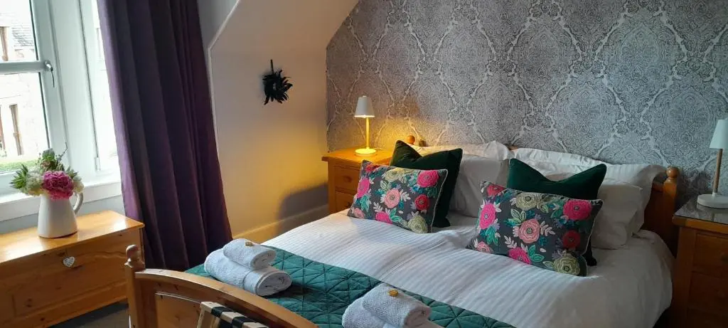 a bedroom with a bed with pillows and a window at Strome Lodge in Inverness