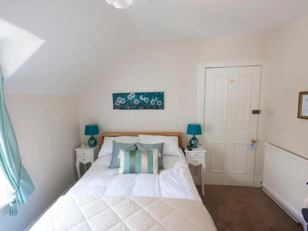 a bedroom with a white bed with two night stands at The Ness Guest House in Inverness