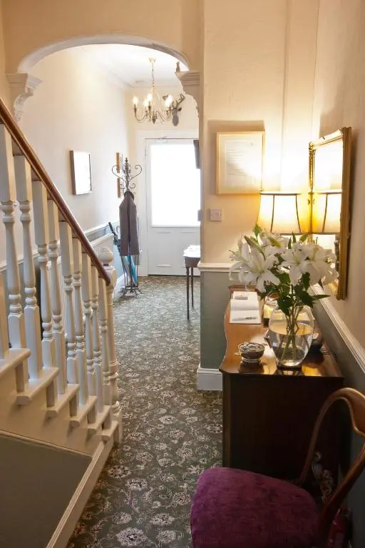 a hallway with a staircase with a vase of flowers at The Ness Guest House in Inverness