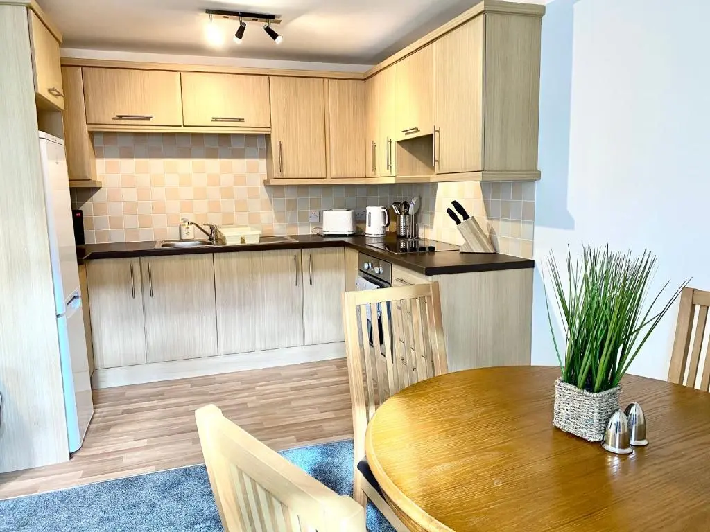 a kitchen with wooden cabinets and a wooden table at Modern Spacious, Near Marina - Commerce Street, Lossiemouth - Free Parking, WiFi in Lossiemouth