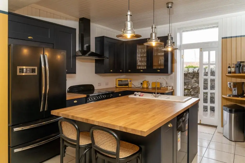 a kitchen with black cabinets and a wooden counter top at 50TheHighstreet by The House of Danu in Kingussie