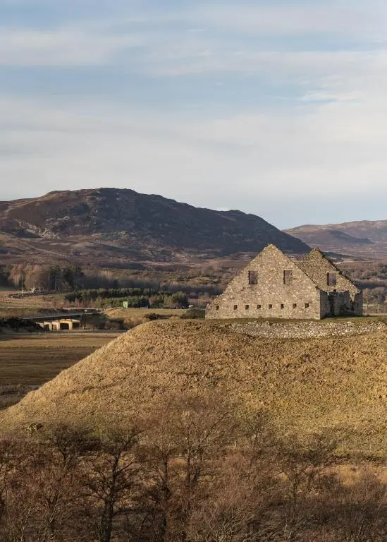 an old building on a hill with mountains in the background at 50TheHighstreet by The House of Danu in Kingussie