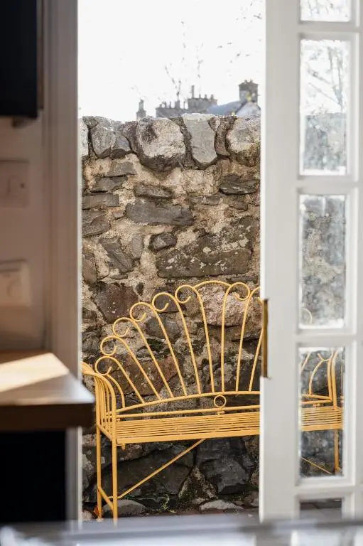 a bench sitting in front of a stone wall at 50TheHighstreet by The House of Danu in Kingussie