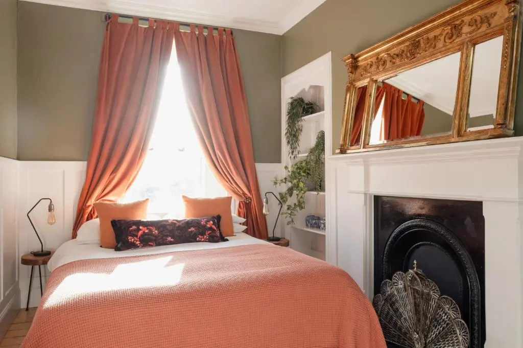 a bedroom with a bed with a fireplace and a window at 50TheHighstreet by The House of Danu in Kingussie