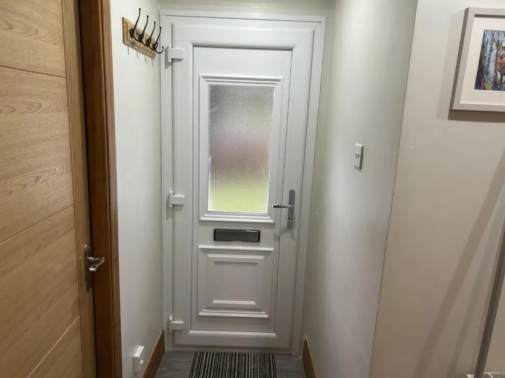 a white door with a window in a hallway at Bright Star Lodge in Spean Bridge