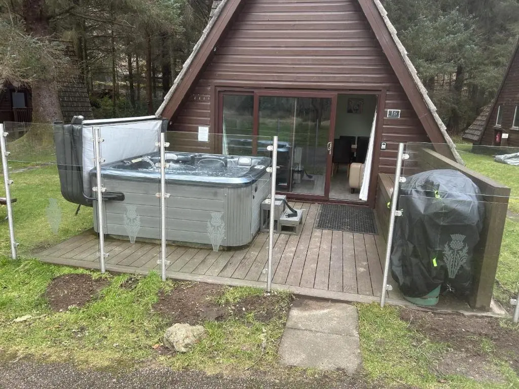 a hot tub on a deck in front of a house at Bright Star Lodge in Spean Bridge