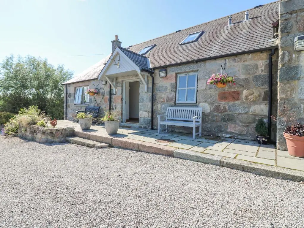 a stone cottage with a bench in front of it at Stable Cottage in Inverurie