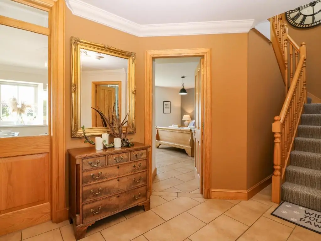a hallway with a staircase and a dresser and a mirror at Stable Cottage in Inverurie