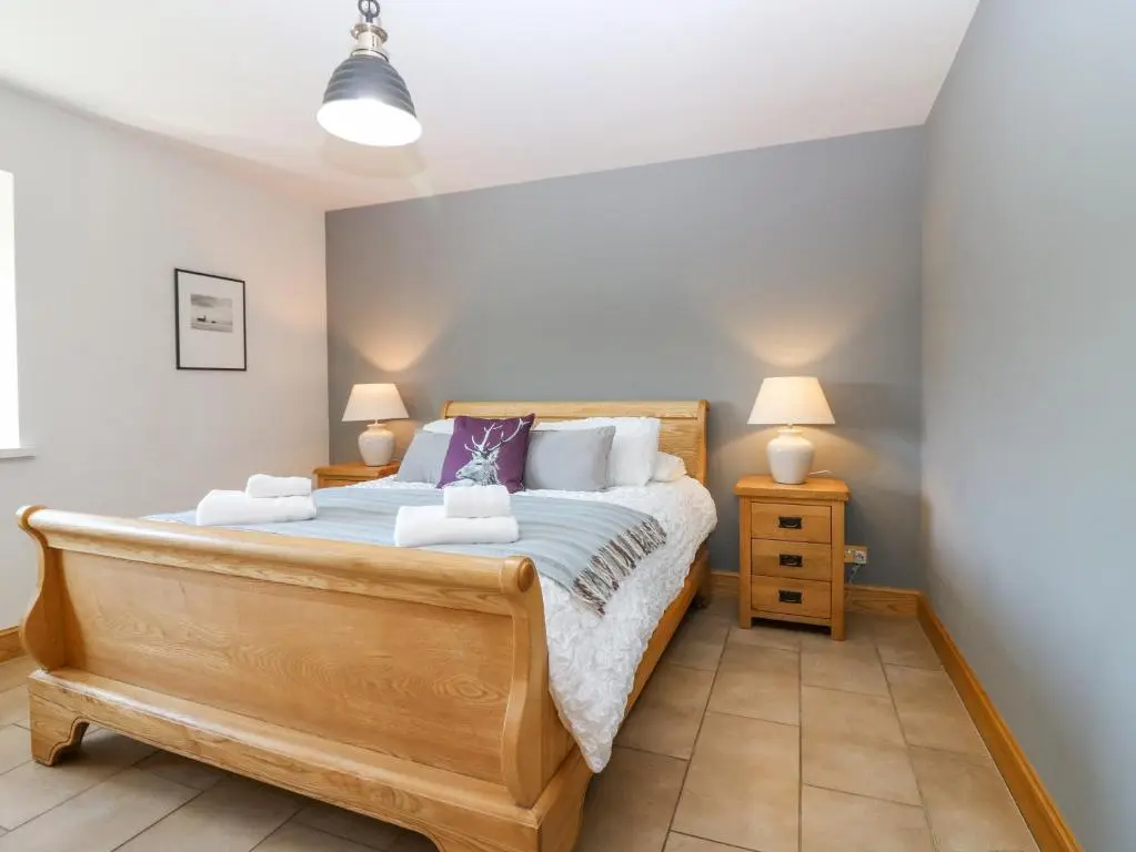 a bedroom with a large bed with two lamps at Stable Cottage in Inverurie