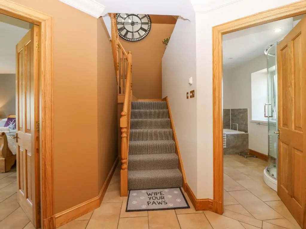 a staircase in a house with a clock on the wall at Stable Cottage in Inverurie