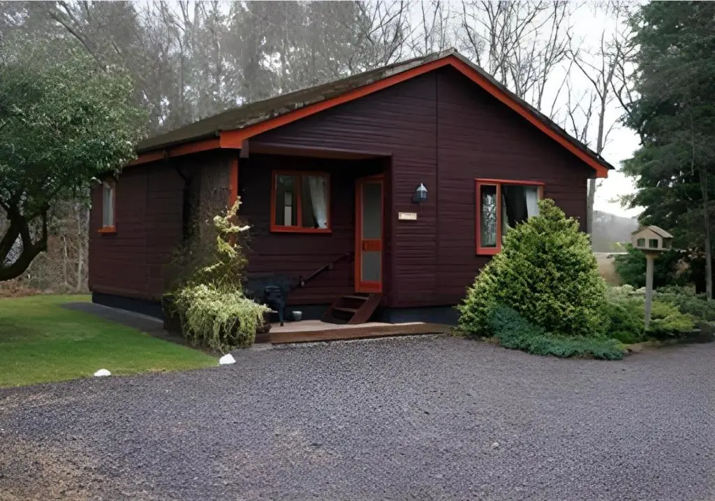 a small cabin with a red door on a driveway at Tullochwood Lodges in Forres