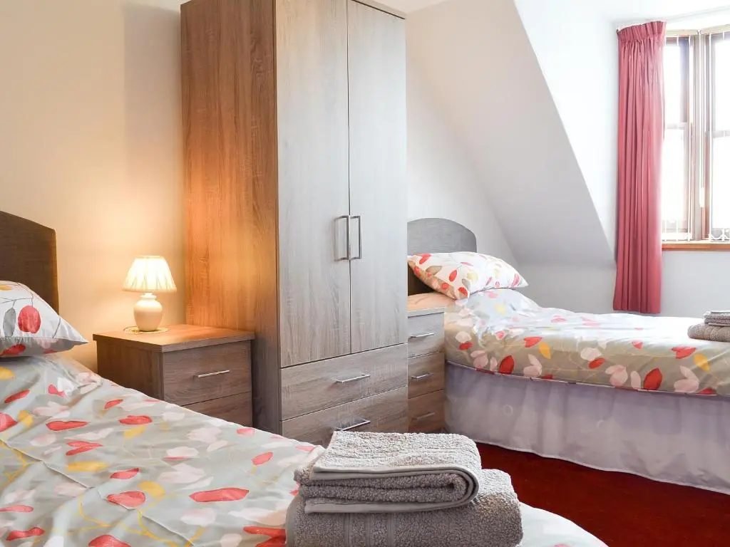 a small bedroom with two beds and a cabinet at Number 12 in Portknockie