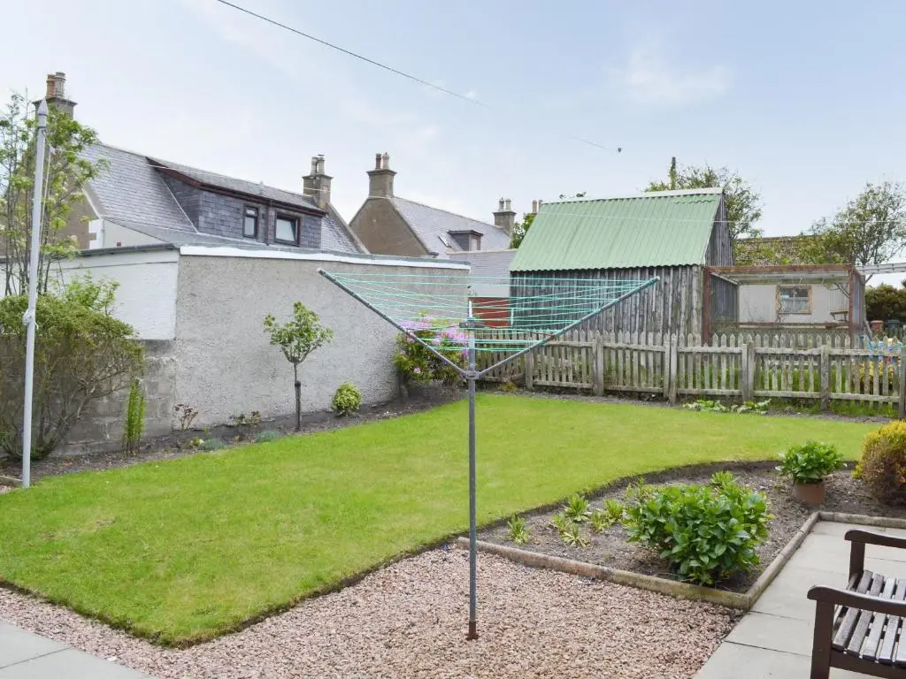 a yard with a garden with a fence and a house at Number 12 in Portknockie