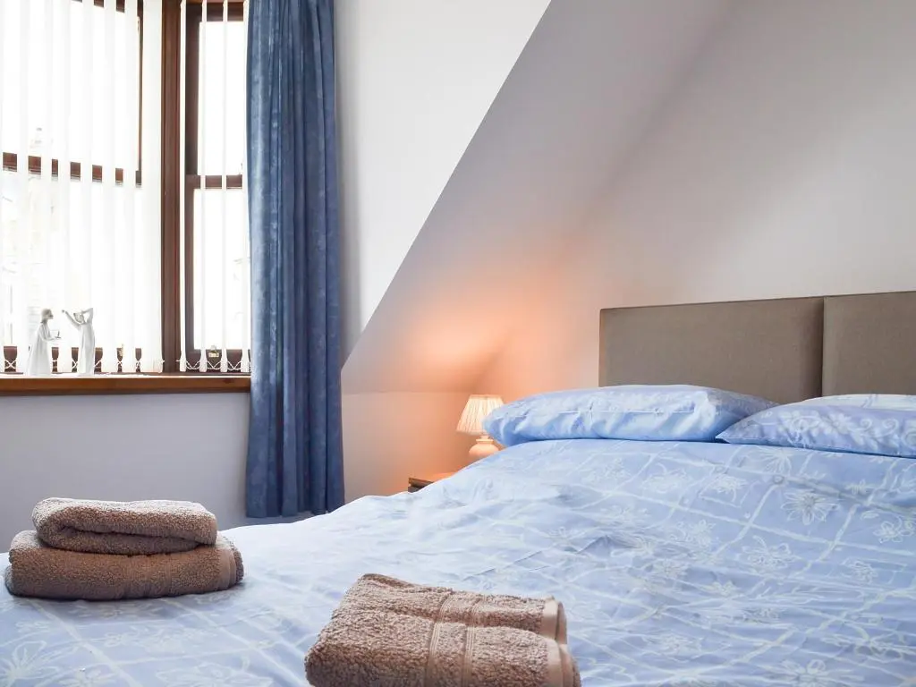 a bedroom with a bed and a window with blue curtains at Number 12 in Portknockie