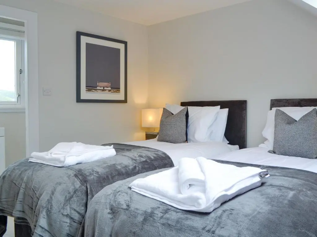 two beds with white towels on them in a room at Darroch View in Ballater