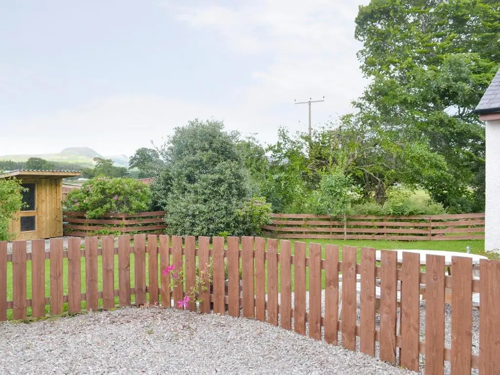 a wooden fence in front of a yard at North Lodge Gate House in Urray