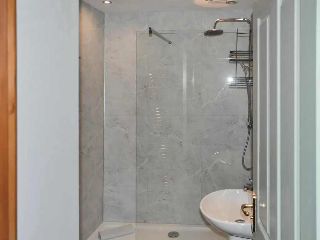 a bathroom with a shower with a toilet and a sink at North Lodge Gate House in Urray