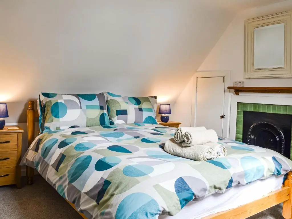 a bedroom with a bed and a fireplace at Needle Cottage in Cullen