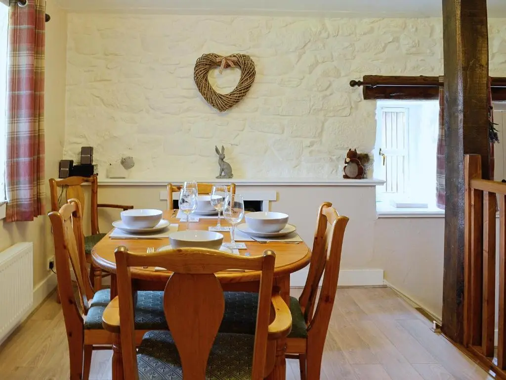 a dining room with a wooden table with chairs at Woodside Cottage in Auchnastank