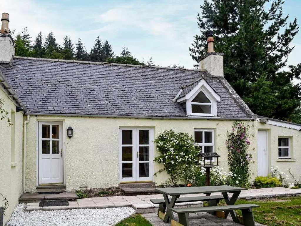 a cottage with a picnic table in front of it at Corrennie School Cottage in Whitehouse