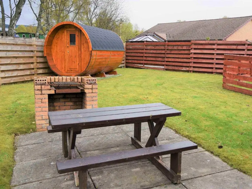 a picnic table in a backyard with a brick oven at Bonnie Doon in Aviemore
