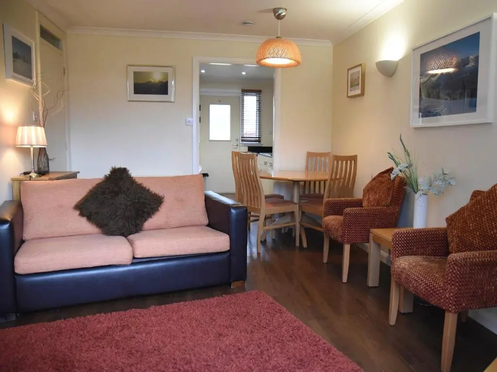 a living room with a couch and a dining room at Bonnie Doon in Aviemore