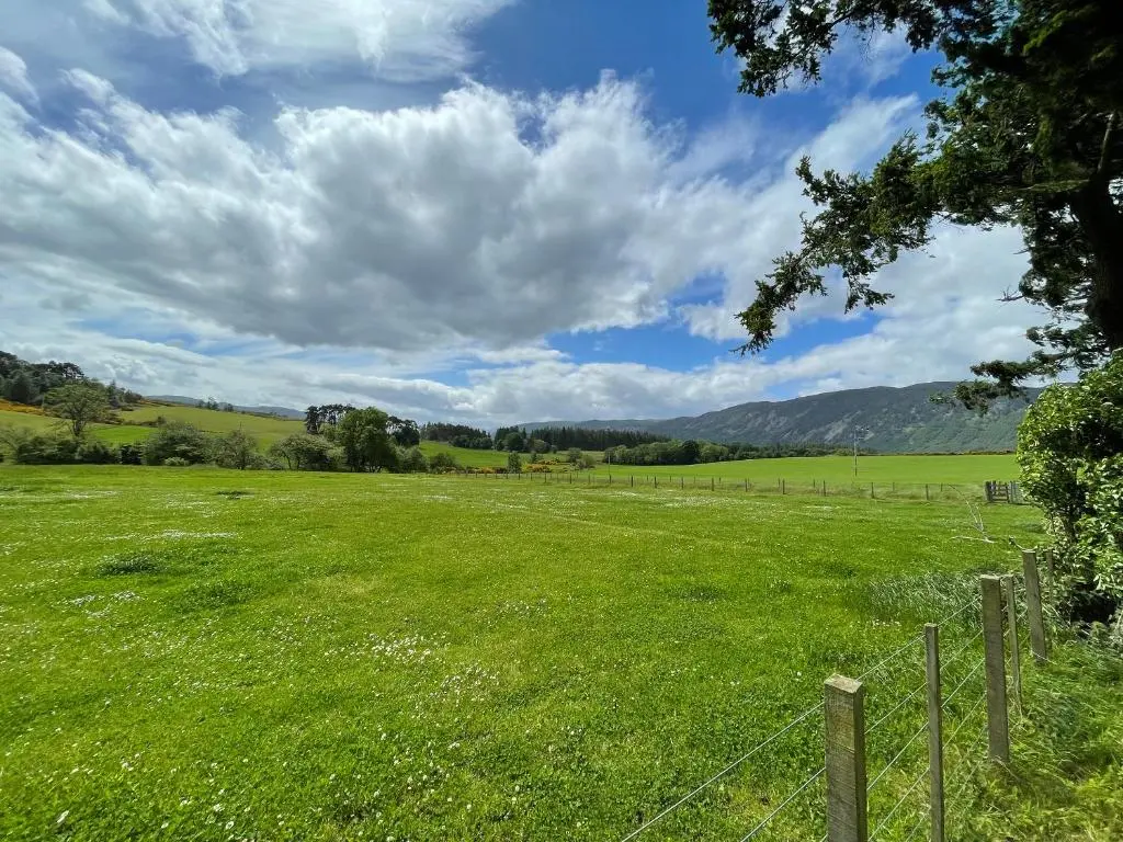 a field of green grass with a fence at Darris Farmhouse in Lochend