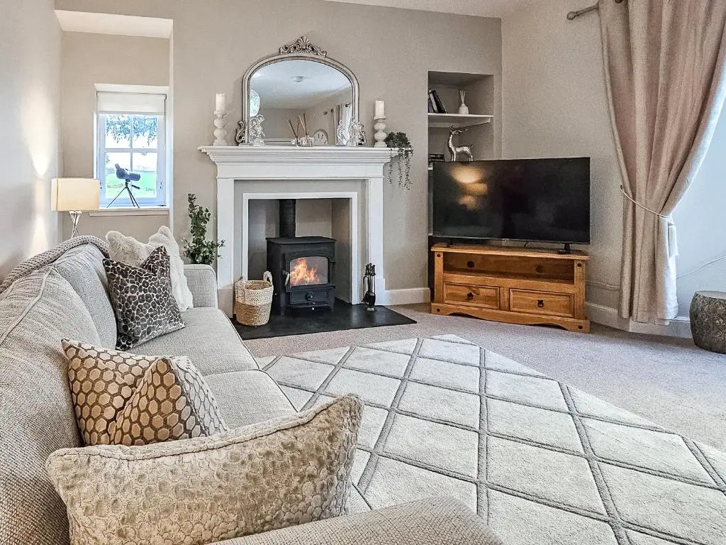 a living room with a fireplace and a television at Darris Farmhouse in Lochend