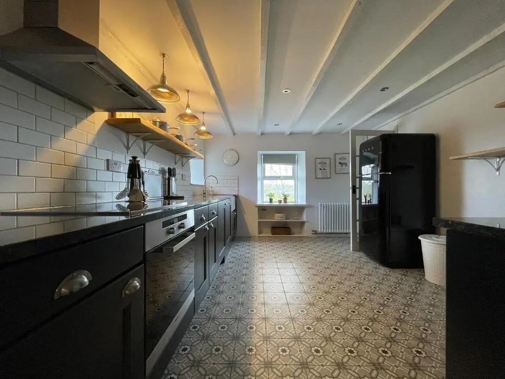 a kitchen with a black refrigerator and a tile floor at Lower Hilton Cottage in Culrain