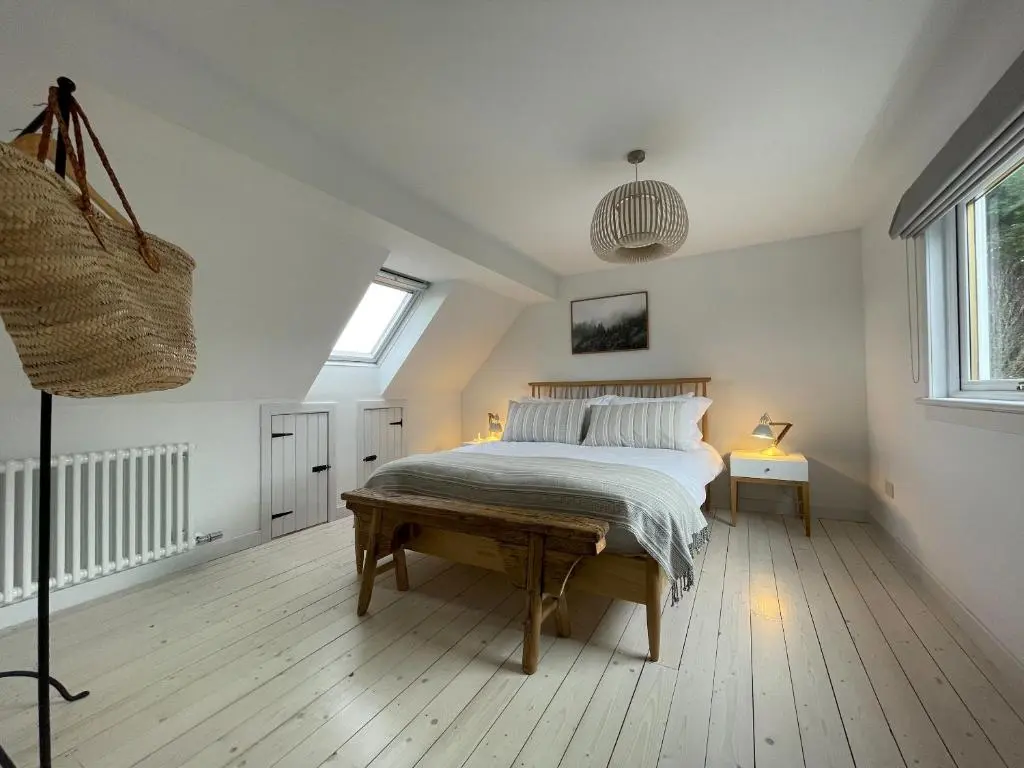 a bedroom with a bed with a wooden floor at Lower Hilton Cottage in Culrain