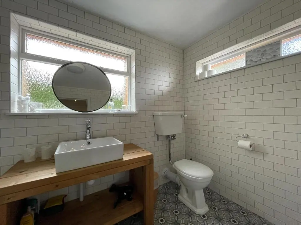 a bathroom with a toilet and a sink and a mirror at Lower Hilton Cottage in Culrain