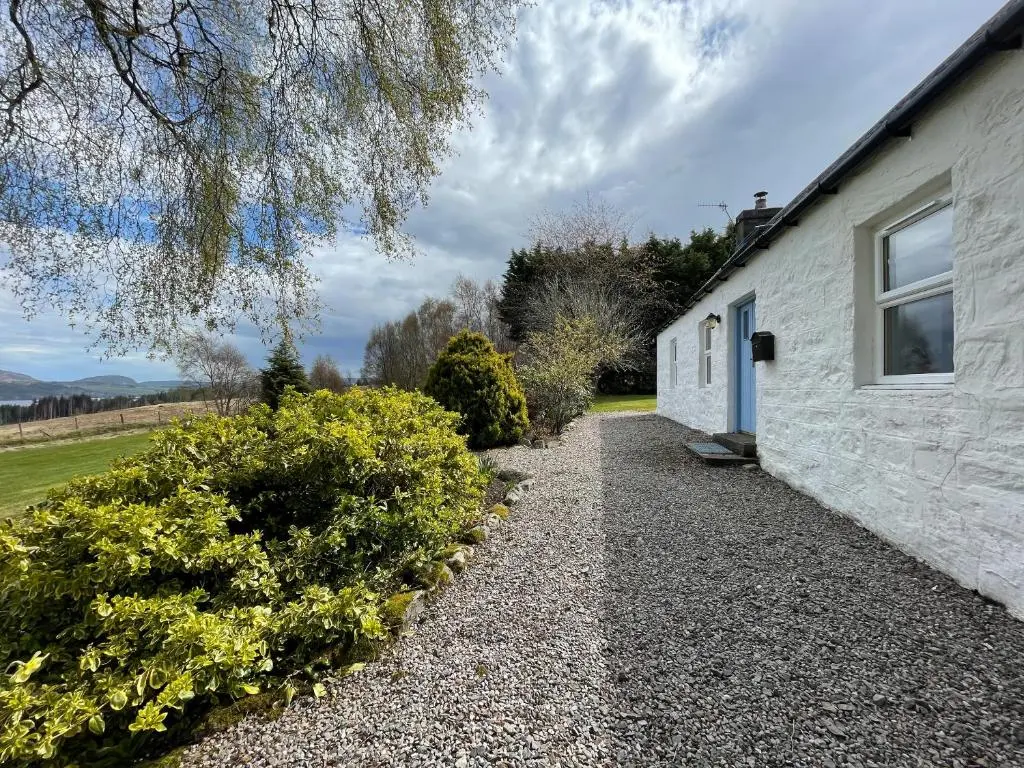 a stone house with a gravel driveway at Lower Hilton Cottage in Culrain