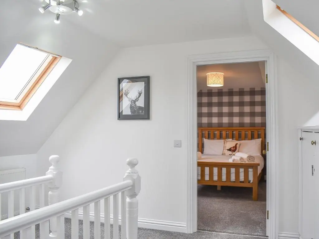 a bedroom with a bed in a room with stairs at 1 Dalbuaick Farm Cottage in Carrbridge