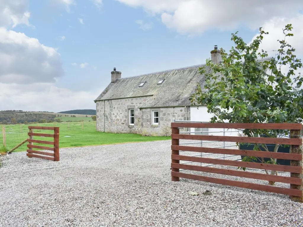 a barn and a fence in front of a house at 1 Dalbuaick Farm Cottage in Carrbridge