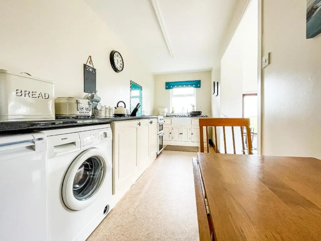 a kitchen with a washing machine and a wooden table at Fourpenny Studio - Uk34745 in Embo