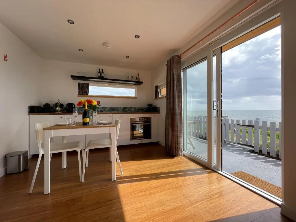 a kitchen with a table and a view of the ocean at Sunrise Summerhouse in Hilton of Cadboll