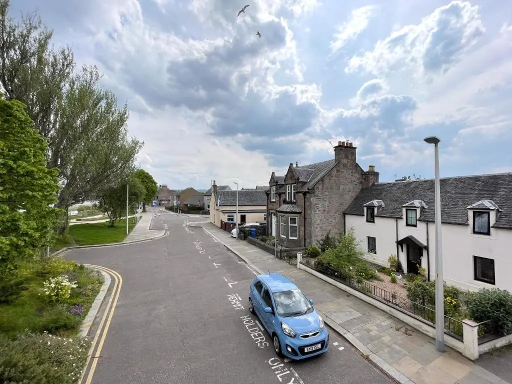 a blue car parked in a parking lot next to houses at Stanford House in Inverness