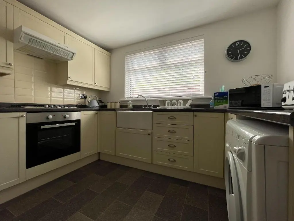 a kitchen with white cabinets and a clock on the wall at Stanford House in Inverness