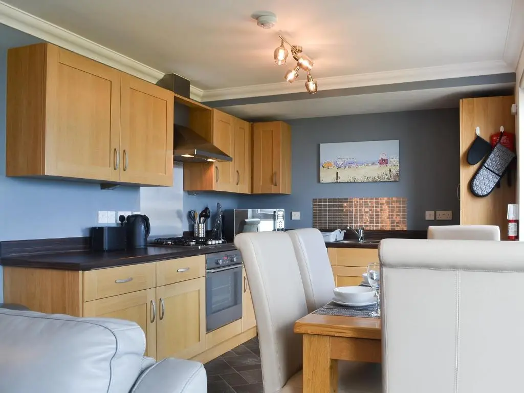 a kitchen with wooden cabinets and a table with chairs at Aurora in Lossiemouth