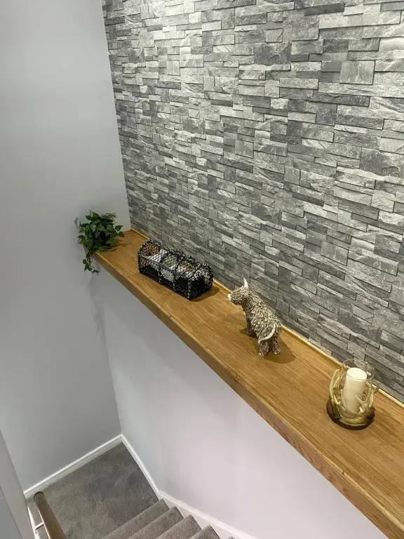a cat sitting on a wooden shelf next to a brick wall at Town centre 3 bed luxury apartment in Wick