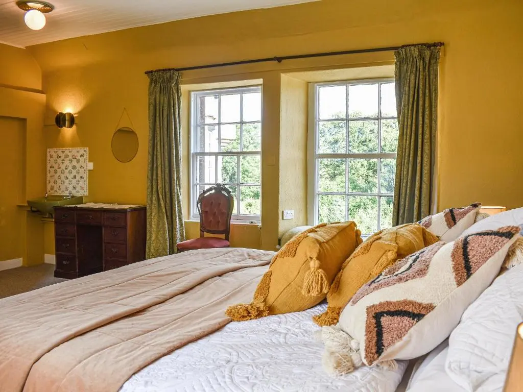 a bedroom with a bed and a chair and windows at Hayfield - Uk35890 in Turriff