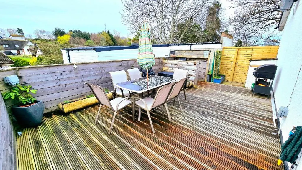 a patio with a table and chairs and an umbrella at Four Winds Holiday Let in Nairn