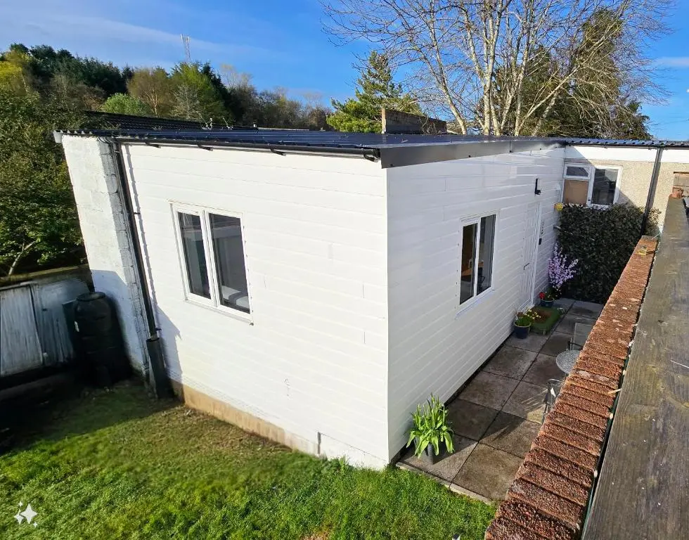 a white shed with a black roof on a yard at Four Winds Holiday Let in Nairn
