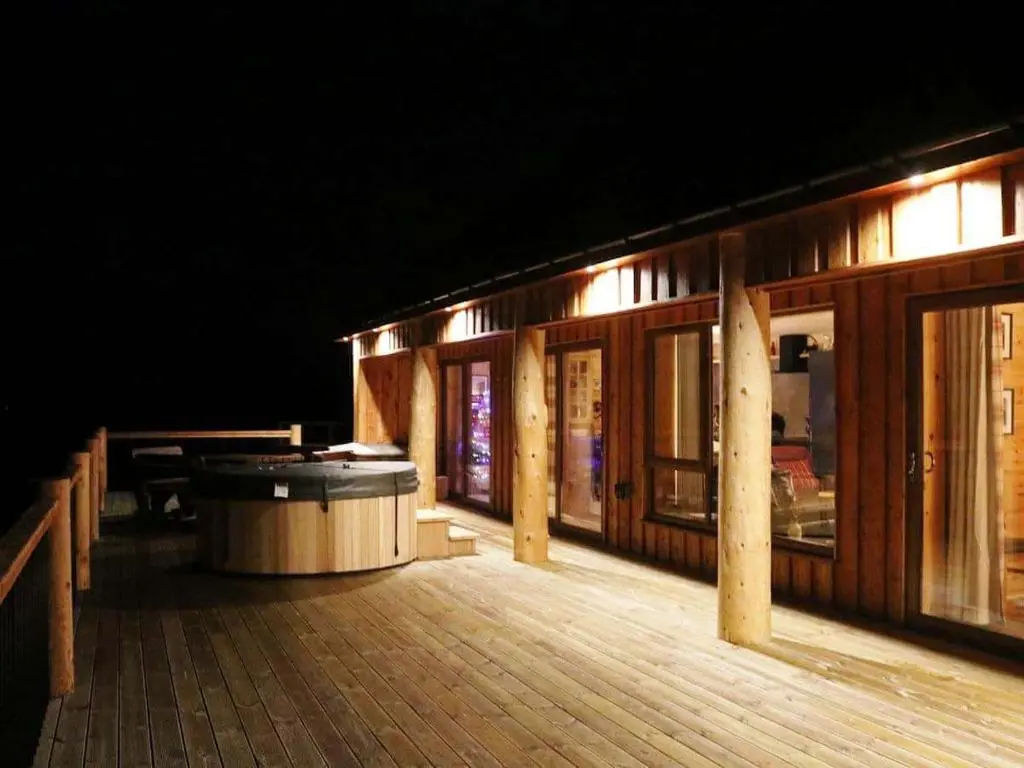 a large deck with a tub on the side of a building at Red Kite & Osprey Lodges in Rhilochan